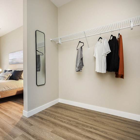 a bedroom with a bed, a chair, and clothes hanging on a rack.