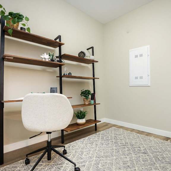 a room with a white chair and shelves with plants on them.