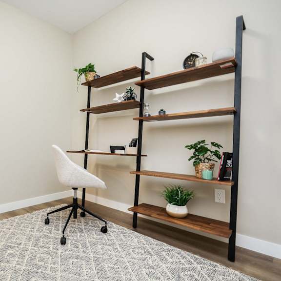 a room with a white chair and a shelf with plants on it.