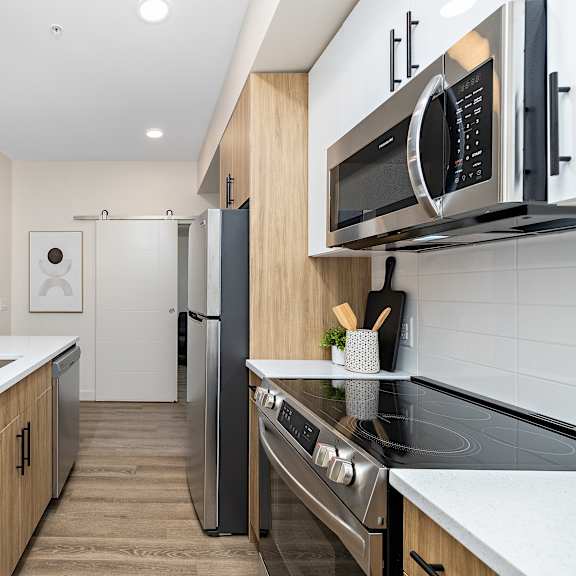 galley kitchen with wood cabinets and white countertops at mac and mullen apartments, edmonton, ab