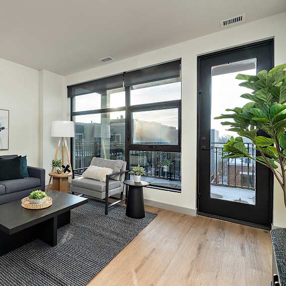 a modern living room with a grey couch, a coffee table, and a large window.at raymond block, edmonton, ab