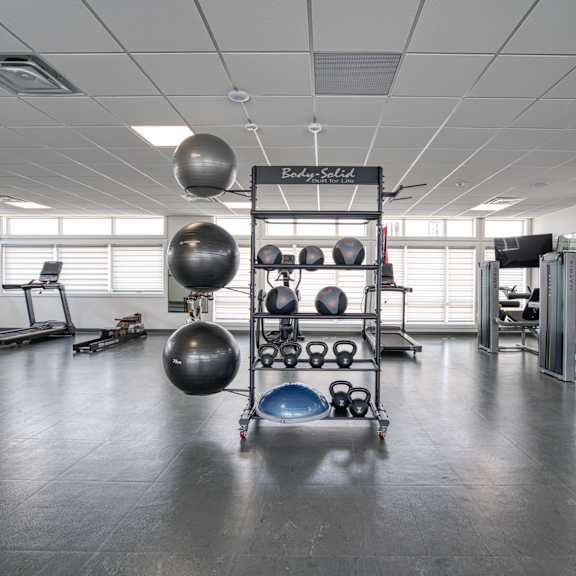a gym with a variety of equipment including weights and exercise balls.