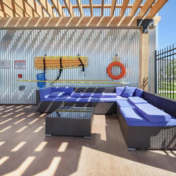 a wooden deck with a blue couch and a surfboard on the wall.