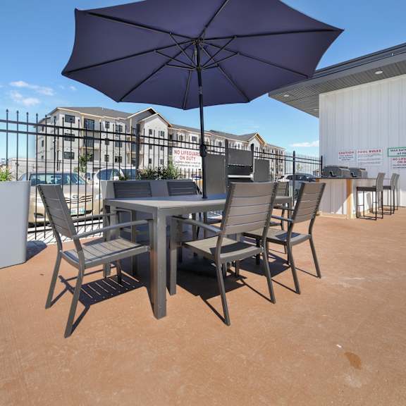 a table with chairs and an umbrella is set up on a patio.