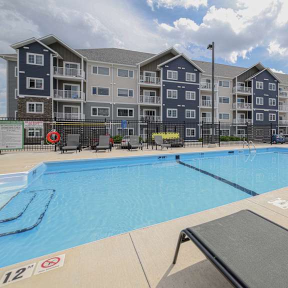 a swimming pool in front of a large apartment complex.