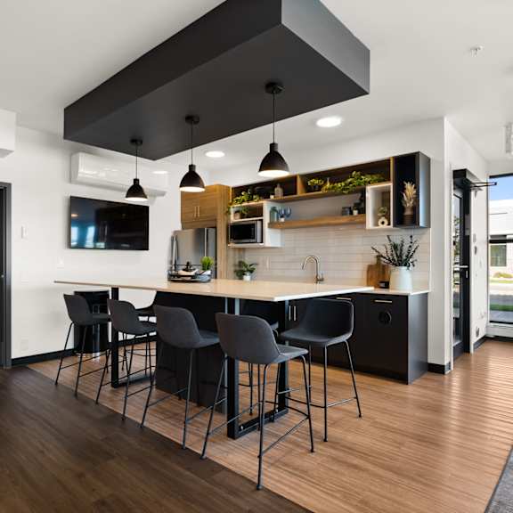 a modern kitchen with black chairs and a wooden floor.