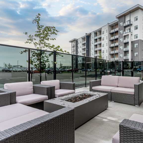 a patio with white couches and grey wicker chairs.