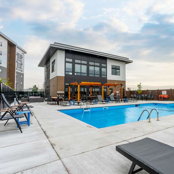 a pool area with a building and lounge chairs.