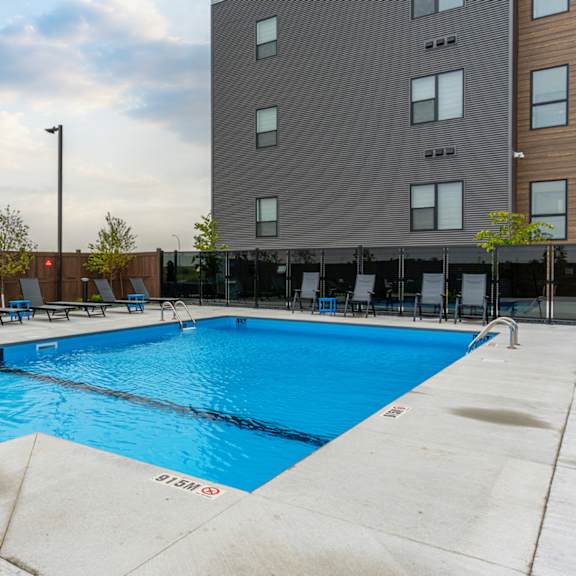a large blue swimming pool in front of a tall building.