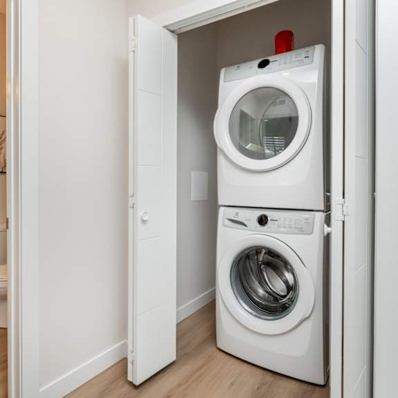 a white washing machine is in a small white door.