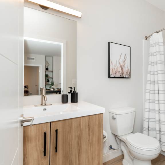 a white bathroom with a toilet, sink, and a basket.