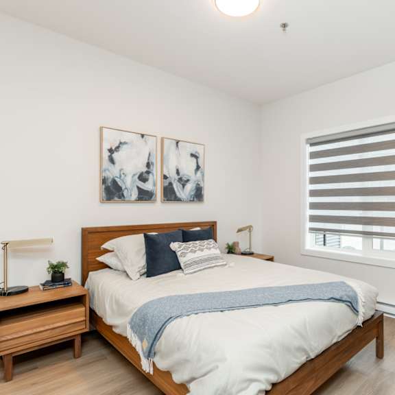 a bedroom with a bed, nightstand, and two framed pictures on the wall.