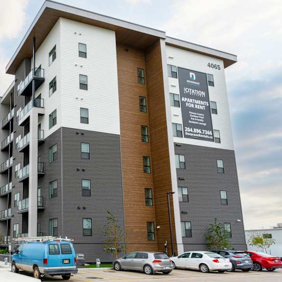 a large apartment building with a parking lot in front.