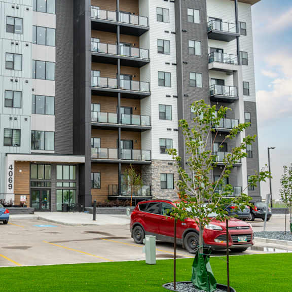 a red car is parked in a parking lot in front of a building.