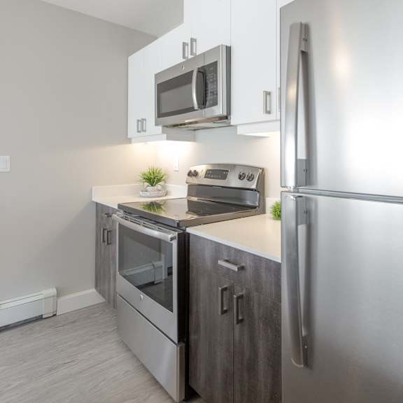 a modern kitchen with stainless steel appliances and wooden flooring.