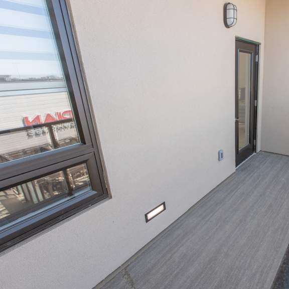 a balcony with a grey railing and a black door.