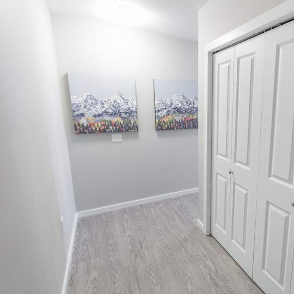 a room with a white door and two pictures of mountains on the wall.