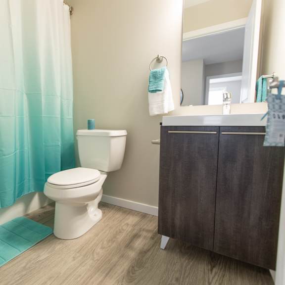 a white toilet sits in a bathroom with a blue shower curtain.
