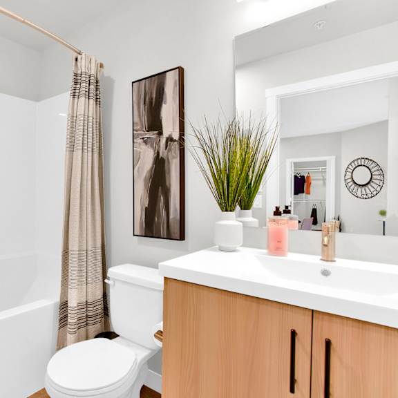 modern bathroom with white vanity and tub at plaza apartments, alberta