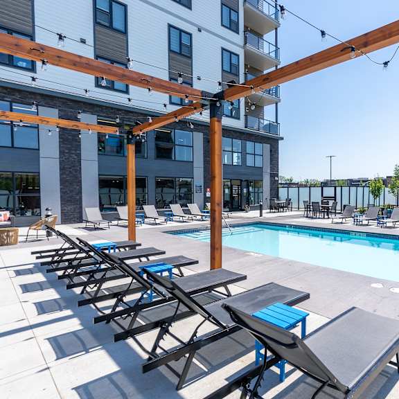 a pool area with sun loungers and a building in the background.