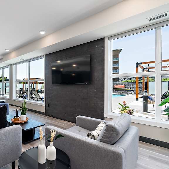 a modern living room with grey couches and a flat screen tv.