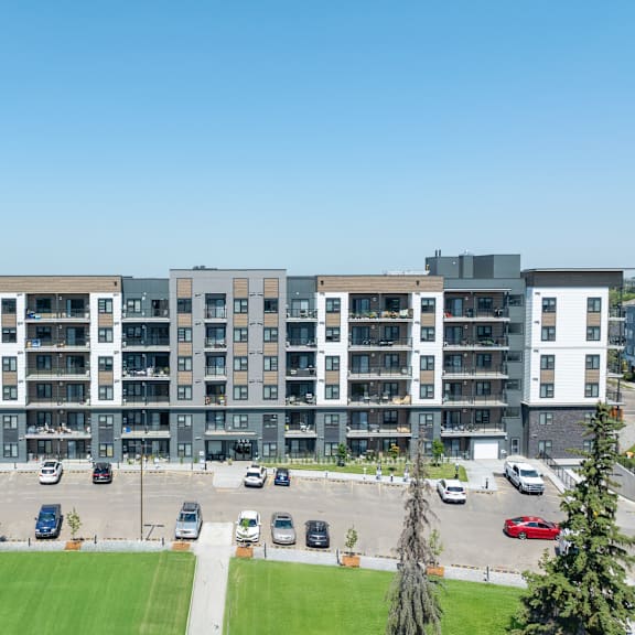a modern apartment complex with a parking lot in front.