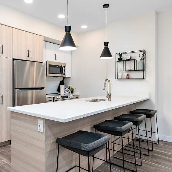 a kitchen with a white countertop and black bar stools.