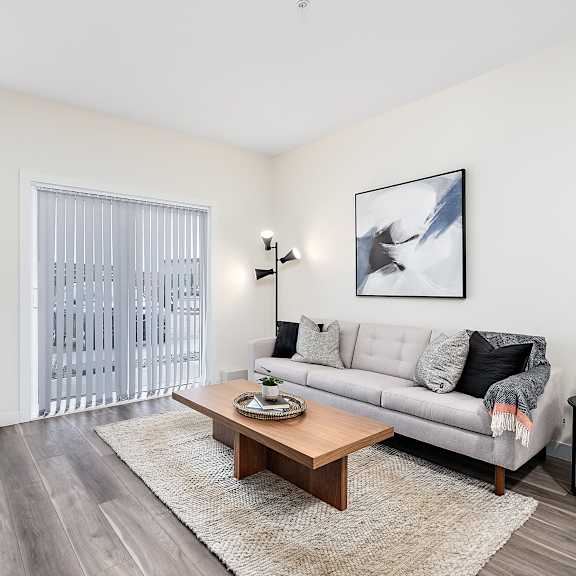 a living room with a grey couch, a wooden coffee table, and a flat screen tv.