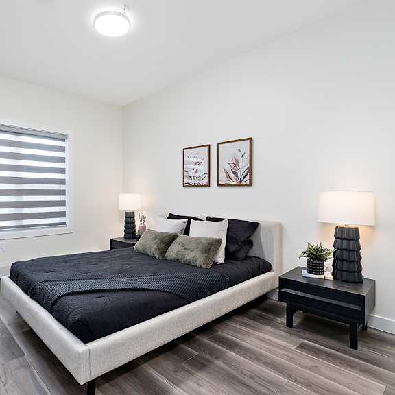 a bedroom with a large bed and a small table with a plant on it.