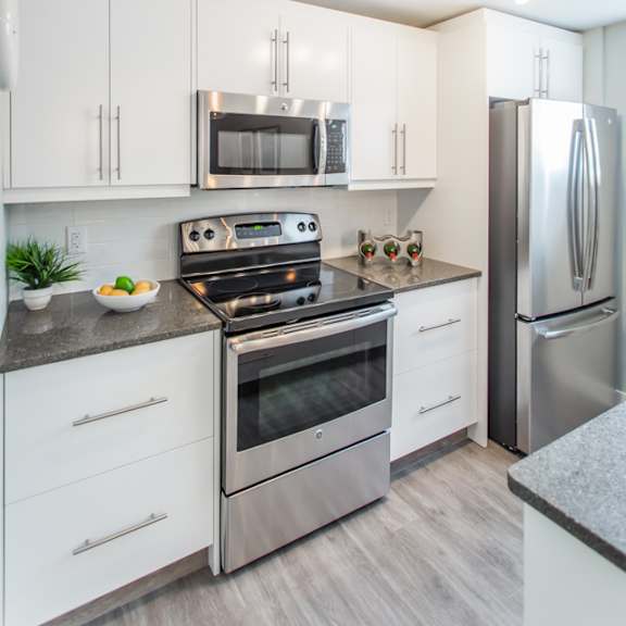 a modern kitchen with stainless steel appliances and white cabinets.