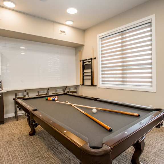a pool table with a brown cloth and two pool cues.