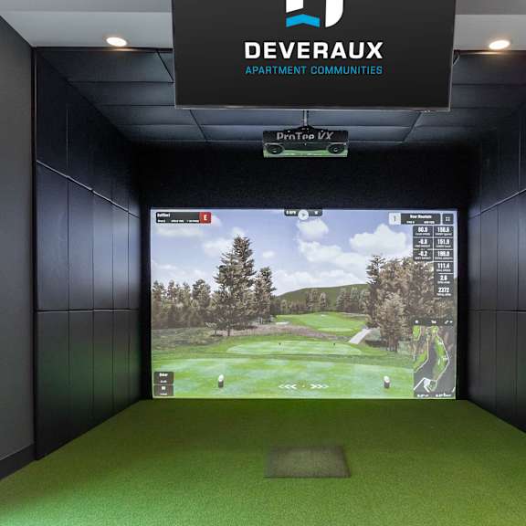 a room with a green carpet and a screen showing a golf course.