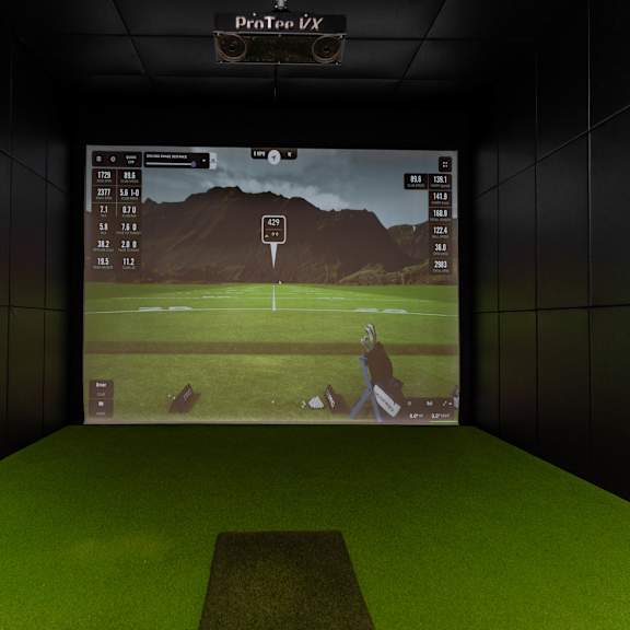 a golf simulator setup with a screen showing a golfer on a course.at vibe apartments at arbour lake, calgary, t3g 4j2