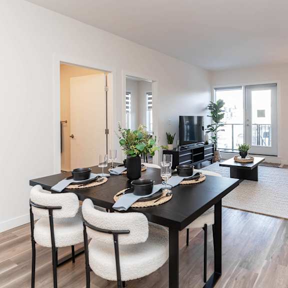 a modern dining room with a black table and white chairs.at vibe apartments at arbour lake, calgary