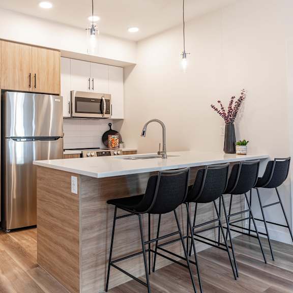 a kitchen with a refrigerator, microwave, and sink.at vibe apartments at arbour lake, alberta, t3g 4j2