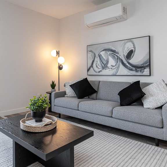 a living room with a grey couch, a black coffee table, and a large abstract painting on the wall.at vibe apartments at arbour lake, calgary, ab t3g 4j2