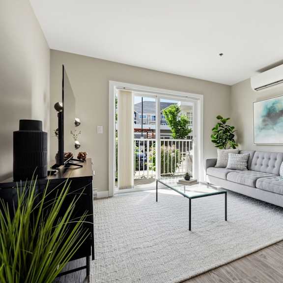 a living room with a grey couch and a painting on the wall.