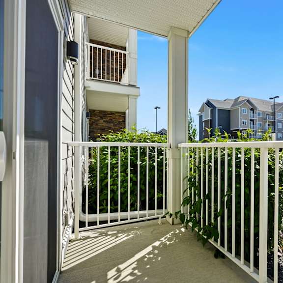 a white metal fence leads to a building.