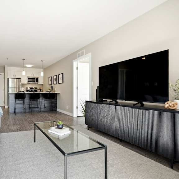 a modern living room with a grey couch and a glass coffee table.