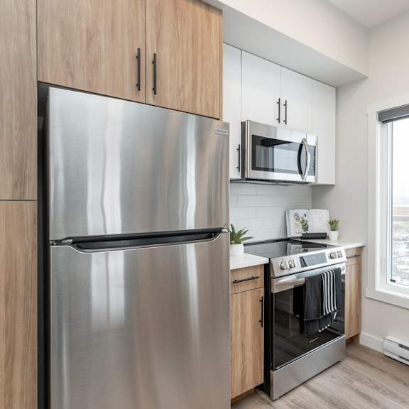 a modern kitchen with a stainless steel refrigerator and oven.at latitude 49 townhomes, manitoba