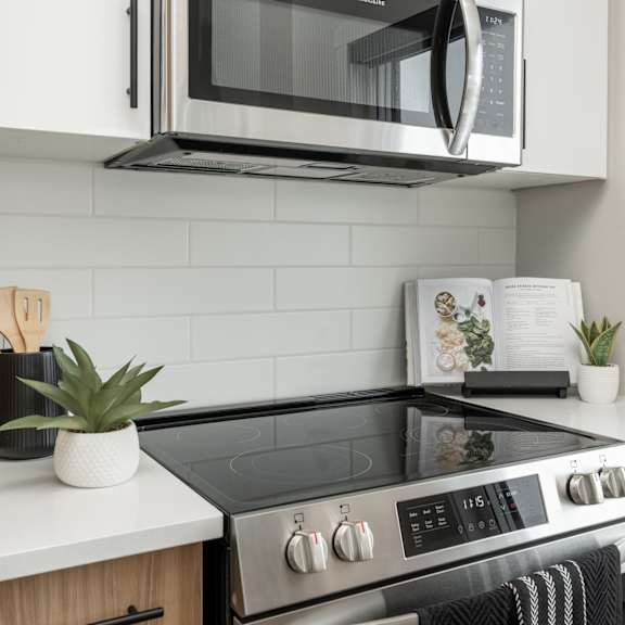 a modern kitchen with a black stove top and white countertops.at latitude 49 townhomes, winnipeg