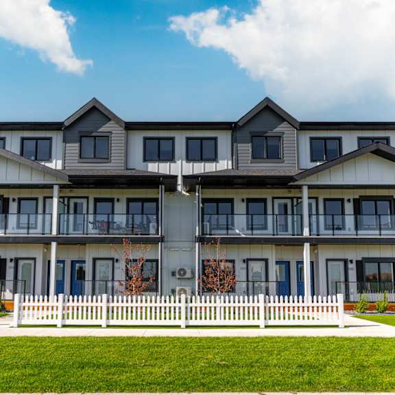 a large white building with a balcony on the second floor.at latitude 49 townhomes, winnipeg, r3x 0m1