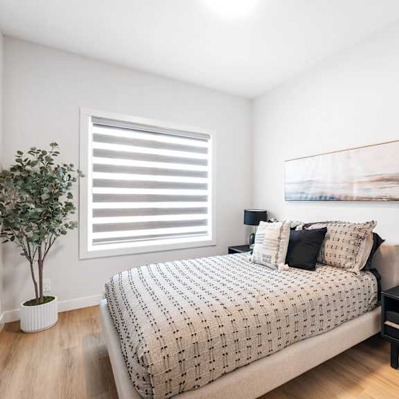 a bedroom with a bed, nightstand, and a plant.