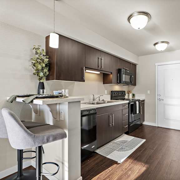 a kitchen with a black fridge and a white chair.