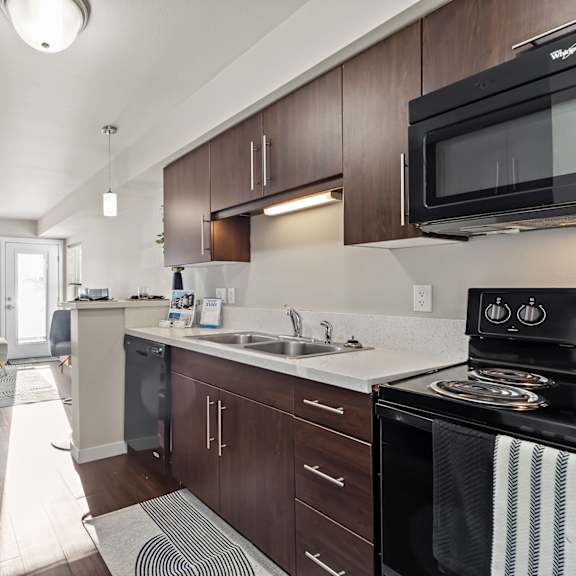 a modern kitchen with dark wood cabinets and a black microwave.