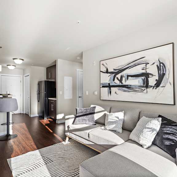a modern living room with a grey couch and a large abstract painting on the wall.