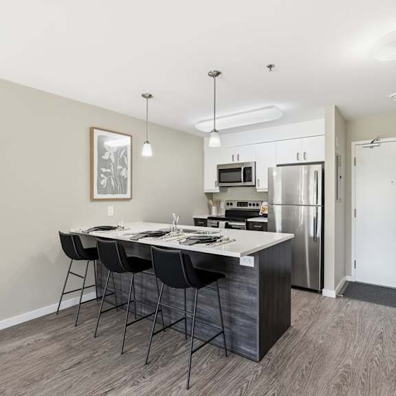 a kitchen with a table and chairs in front of a refrigerator.