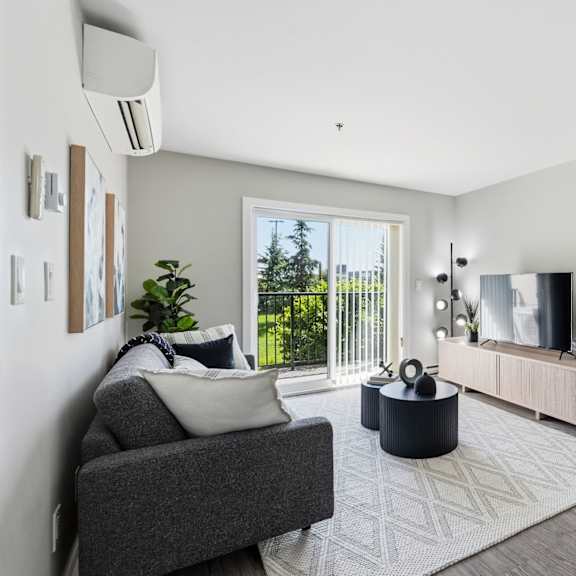 a modern living room with a grey sofa, a round coffee table, and a large window with a view of the outdoors.