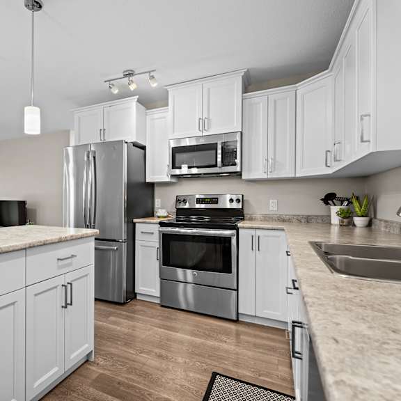 a modern kitchen with stainless steel appliances and white cabinets.