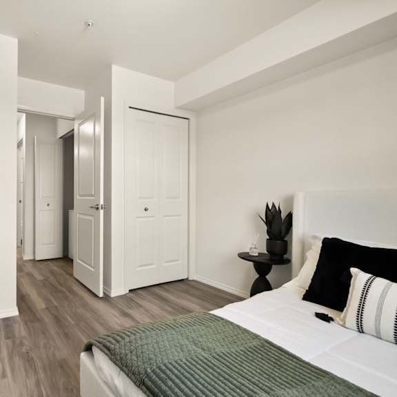 a bedroom with a bed, a nightstand, and a plant.